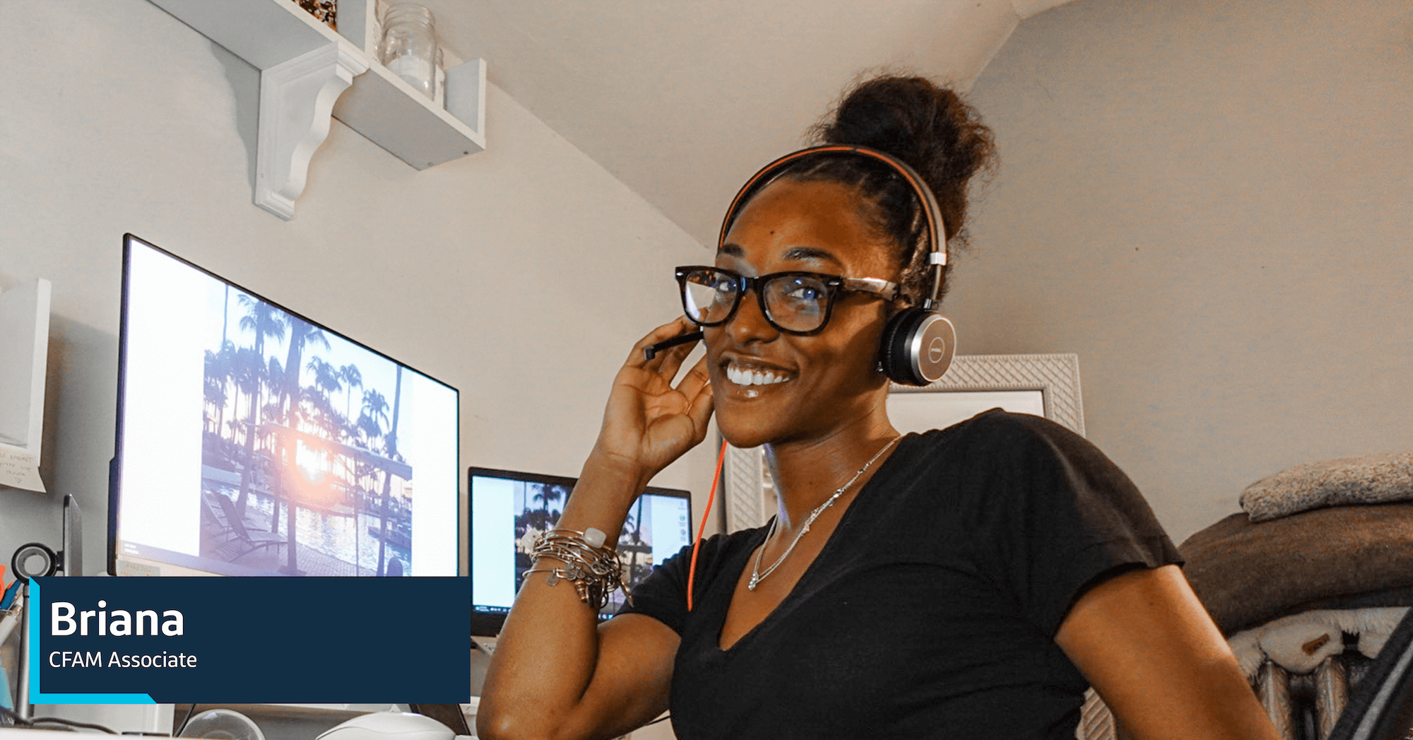Briana, a Capital One CFAM associate, sits at her home office with a headset on, smiling